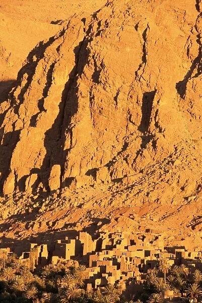 Remains of the kasbah at foot of towering cliffs at sunrise