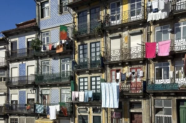 A residential street in the old town with traditional wrought iron balconies, blue and white tiled panels on the outside walls, washing hanging in the sun, Oporto, Portiugal, Europe
