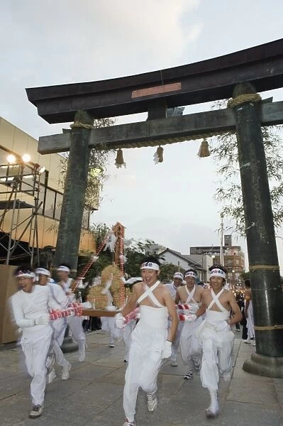 Rice bales being carried through a torii gate at Hadaka Matsuri (Naked Festival)