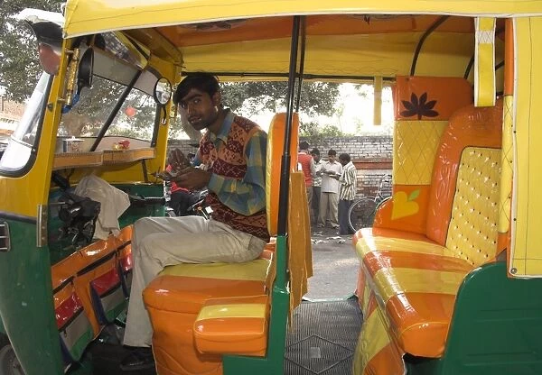 Rickshaw owner sitting in his newly decorated moto rickshaw
