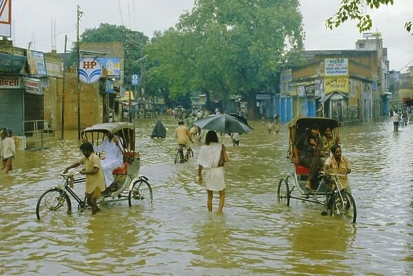 Rickshaws being pushed through the monsoon floods in a town