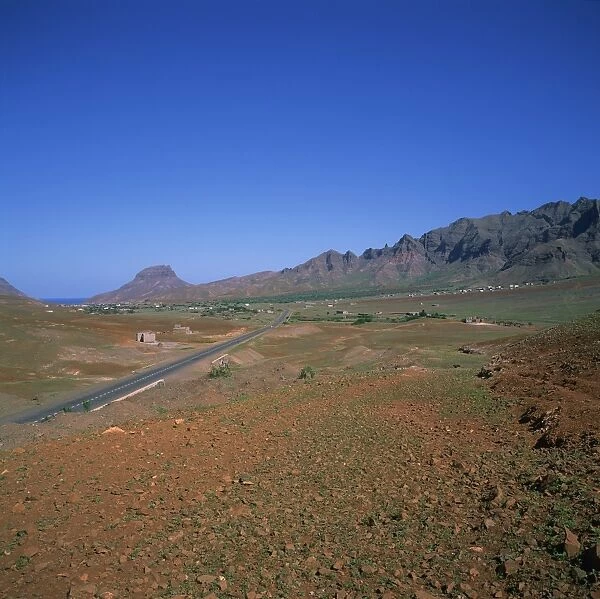 Road across a volcanic crater, with small buildings in the distance, inland on the island of Sao Vicente, Republic of Cape Verde Islands