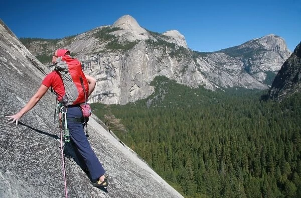 A rock climber ascends slabs at the base of the huge cliff known as The Apron