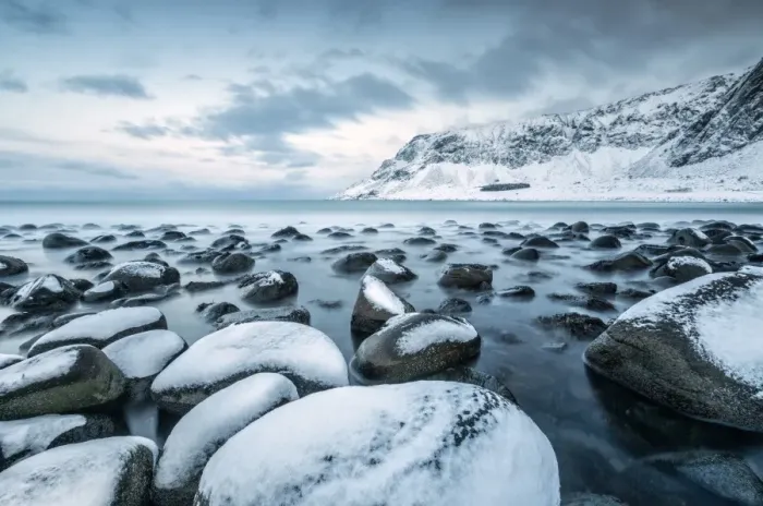 Framed Print : Rocks in the cold sea and snow capped mountains under the blue light of dusk, Unstad