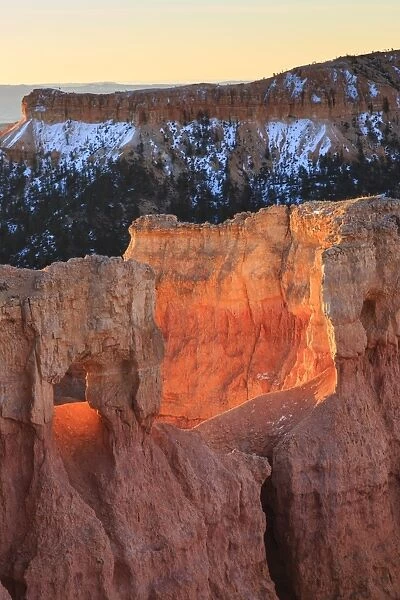 Rocks lit by strong dawn light, snowy backdrop, Queens Garden Trail at Sunrise Point, Bryce Canyon National Park, Utah, United States of America, North America