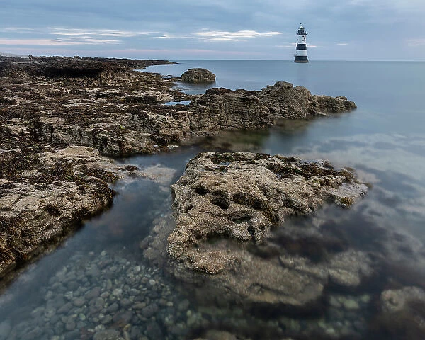 Rocks and Trwyn Du Lighthouse at dawn, Penmon Point, Anglesey, Wales, United Kingdom, Europe