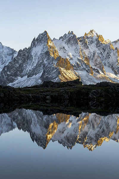 Rocky peaks of Aiguilles de Chamonix reflected in Lacs des Cheserys at sunset