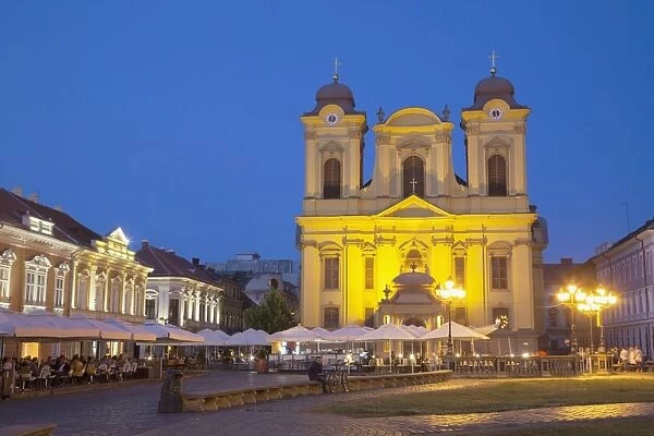 Roman Catholic Cathedral and outdoor cafes in Piata Unirii at dusk, Timisoara, Banat, Romania, Europe