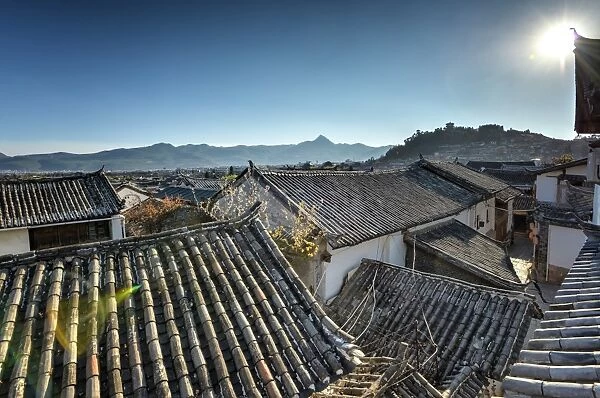 The roofs of Lijiang Old Town, UNESCO World Heritage Site, with Lion Hill silhouetted against a clear sky, Lijiang, Yunnan, China, Asia