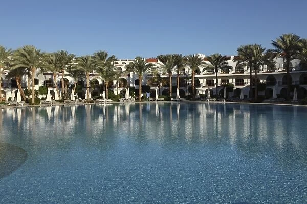 Rooms with verandas overlook a palm fringed swimming pool within the Royal Savoy Resort at Sharm el-Sheikh, Egypt, North