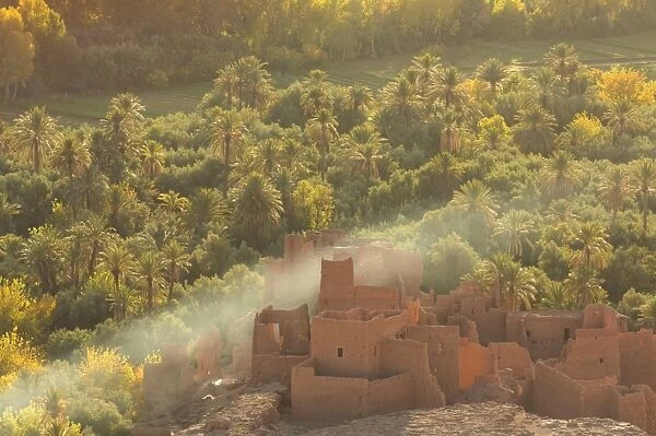 Ruined kasbah in the palmerie near Tinerhir, with smoke from fire swirling through the palm trees