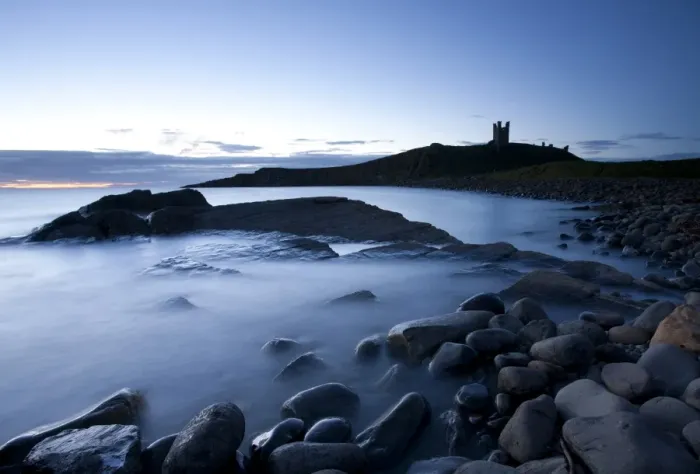 Framed Print : The ruins of Dunstanburgh Castle at dawn with Greymare Rock partly sumberged Framed Print : The ruins of Dunstanburgh Castle at dawn with Greymare Rock partly sumberged