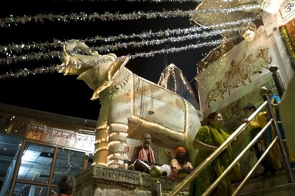 Saddhus sit under decorative marble elephant at the entrance to the Jagdish temple at Diwali