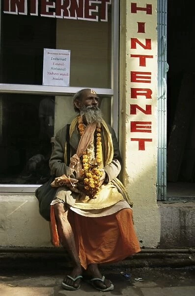 Sadhu (Hindu holy man) sitting outside an internet cafe