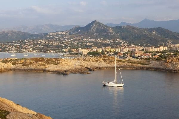 A sail boat in the clear sea around the village of Ile Rousse at sunset, Balagne Region