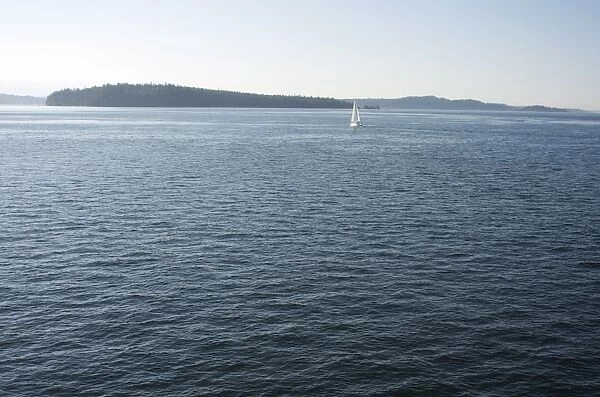Sailboat on the Puget Sound passes Blake Island, Washington State, United States of America