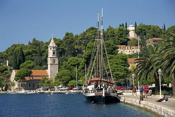Sailing boat on the waterfront, with trees and church in the background at Cavtat