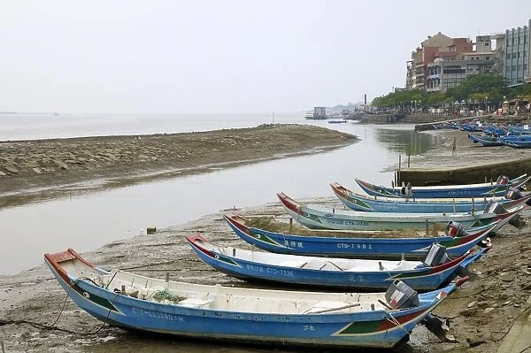 Sampan style fishing boats moored on the shoreline of the Tamsui River estuary at low tide, Tamsui (Danshui), Taiwan, Asia
