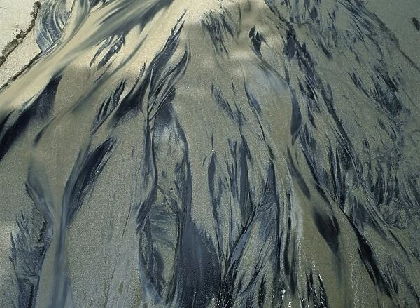 Sand patterns in water, dark volcanic sand lying just below white sand