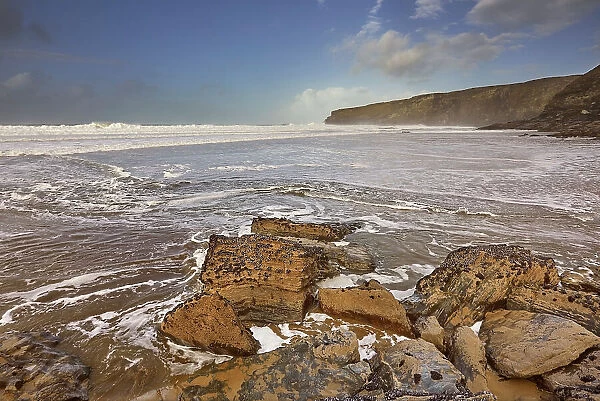 The sand, rocks, surf, cliffs and storm clouds of Cornwall's Atlantic coast, at Trebarwith Strand, near Tintagel, Cornwall, England, United Kingdom, Europe
