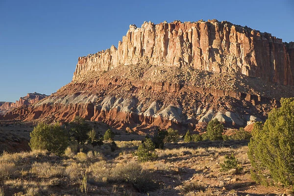 Sandstone cliffs of the Waterpocket Fold towering above Scenic Drive, sunset, Fruita