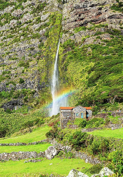 Scenic view of the waterfall of Poco do Bacalhau falling behiend a house with rainbow, Faja Grande, Lajes das Flores, Flores Island (Ilha das Flores), Azores archipelago, Portugal, Atlantic, Europe