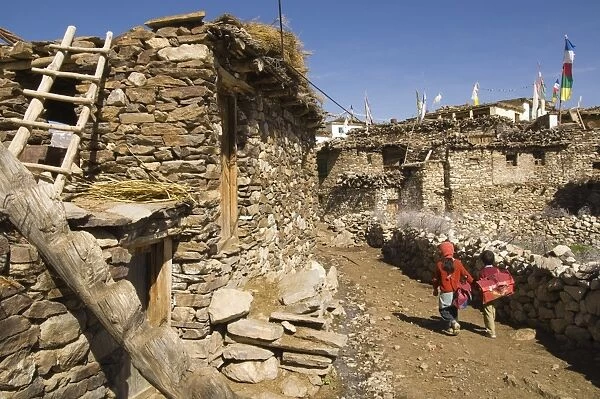 Two schoolchildren and typical stone houses on village street