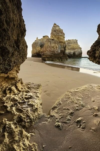 A sea cave frames the ocean and the imposing cliffs at dawn, Praia da Rocha, Portimao