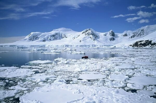 Seascape with ice and snow, and people ice cruising in zodiac, Antarctic Peninsula
