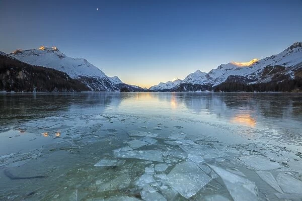 Sheets of ice on the surface of Lake Sils in a cold winter morning at dawn, Engadine