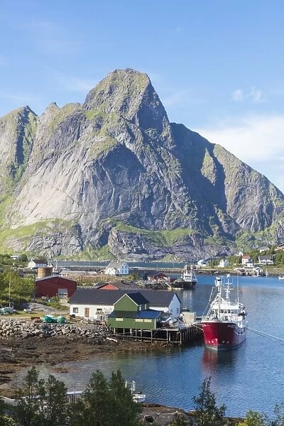 Ship in the blue sea frames the fishing village and the rocky peaks, Reine, Moskenesoya
