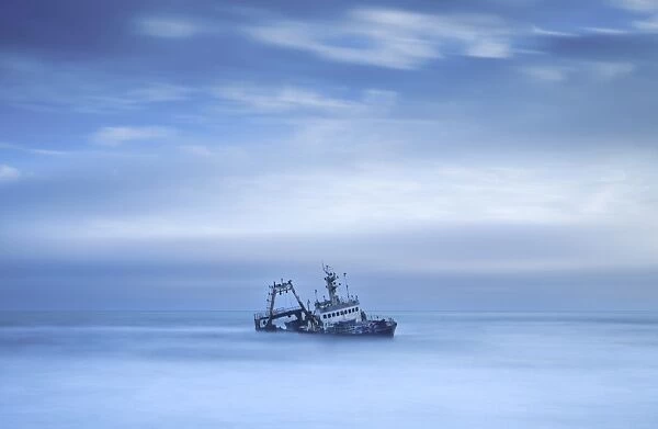 Shipwreck off the Atlantic coast, shot with long exposure to record motion in sea and sky, near Walvis Bay, Namibia, Africa