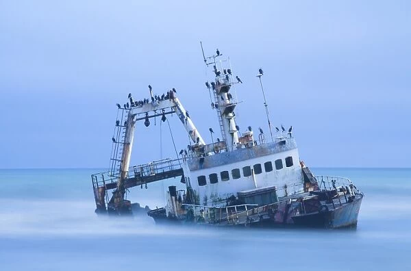 Shipwreck off the Atlantic coast, shot with long exposure to record motion in sea and sky, near Walvis Bay, Namibia, Africa