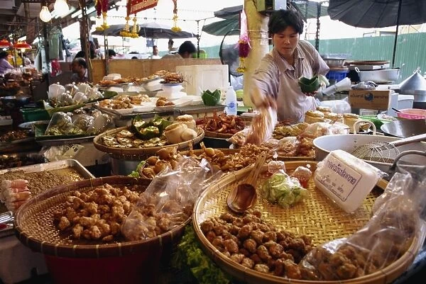 A shopkeeper puts fish cakes on a tray on a stall in