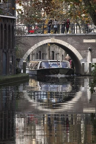A sightseeing barge under a bridge on the Oudegracht Canal in the Dutch city of Utrecht