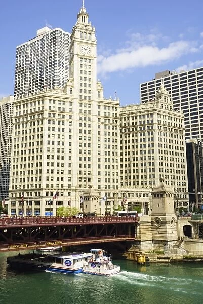 Sightseeing boat passing under DuSable Bridge on the Chicago River with Wrigley Building behind