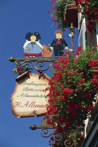 Sign outside traditional patisserie, red flowers prominent, Eguisheim, Haut-Rhin