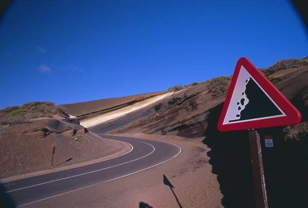 Sign on a road with volcanic stratified rocks in the background