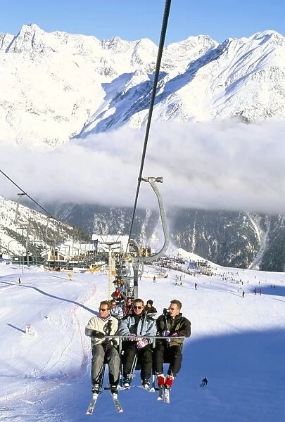 Skiers riding chairlift up to slopes from village of Solden, Tirol Alps
