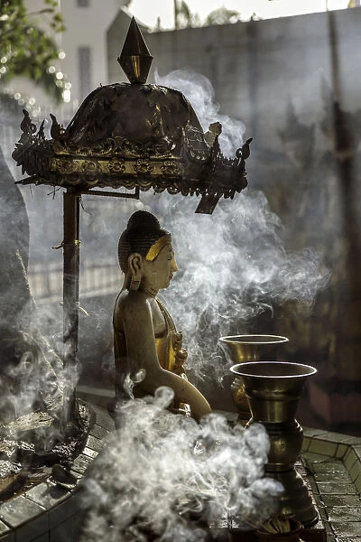 A small Buddha statue at Sule pagoda, surrounded by clouds of smoke with two Kinaree