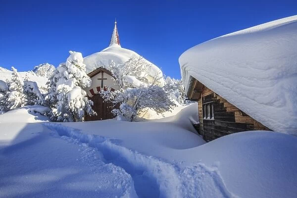 The small church and the house submerged by snow after a heavy snowfall in Maloja