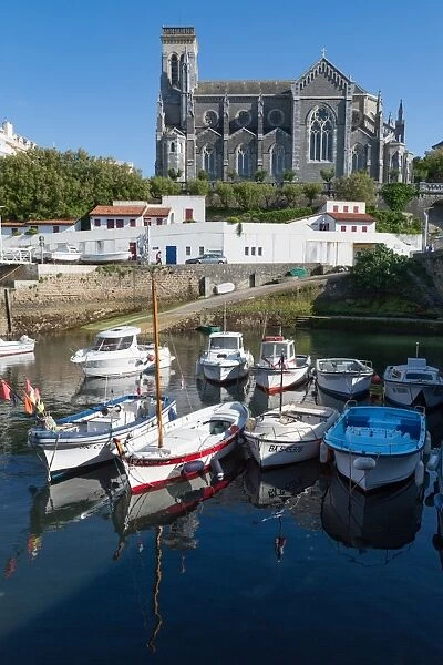Small port with traditional fishing boats and Eglise Sainte Eugenie in Biarritz