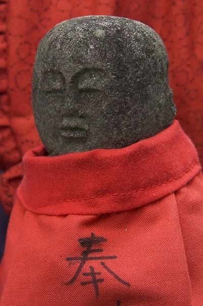 Small stone figure wearing traditional red dress