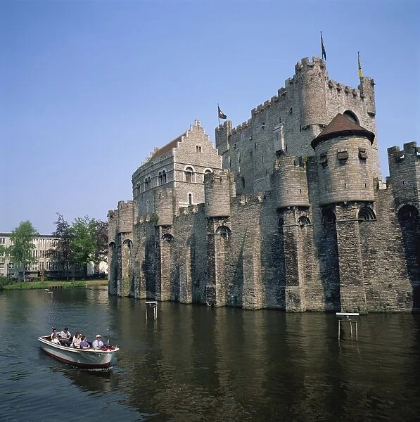 Small tourist boat passing the Castle of the Counts of Flanders in the city of Ghent
