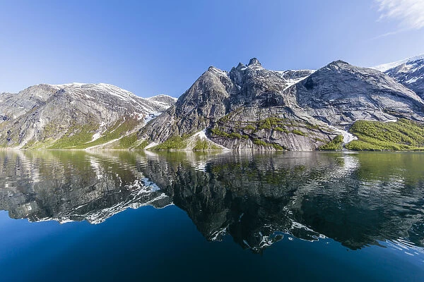 Snow-capped mountains reflected in the calm waters of Nordfjord, deep inside of Melfjord