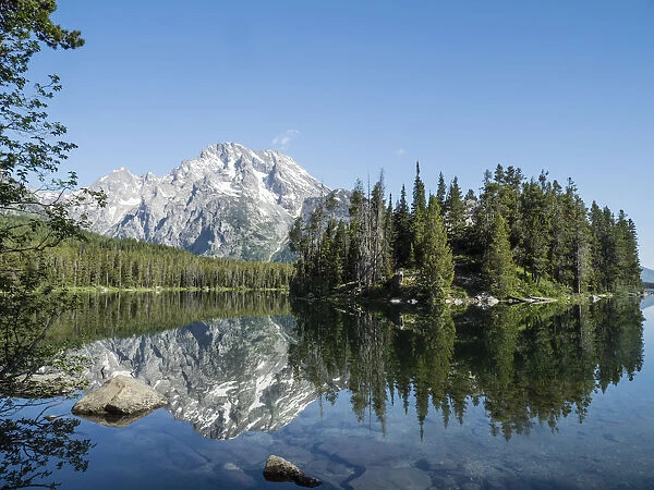 Snow-capped mountains reflected in the calm waters of Leigh Lake, Grand Teton National