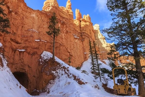 Snow clearing equipment at a tunnel through sunlit red rock in winter, Peekaboo Loop Trail, Bryce Canyon National Park, Utah, United States of America, North America