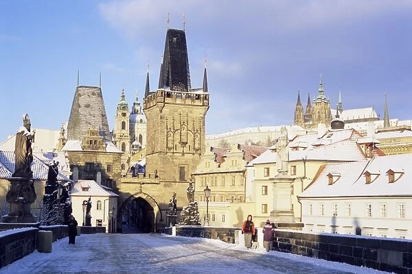 Snow-covered Gothic Charles bridge with Baroque statues, Romanesque and Gothic Malostranske bridge towers and Prague castle, Mala Strana, Prague, Czech