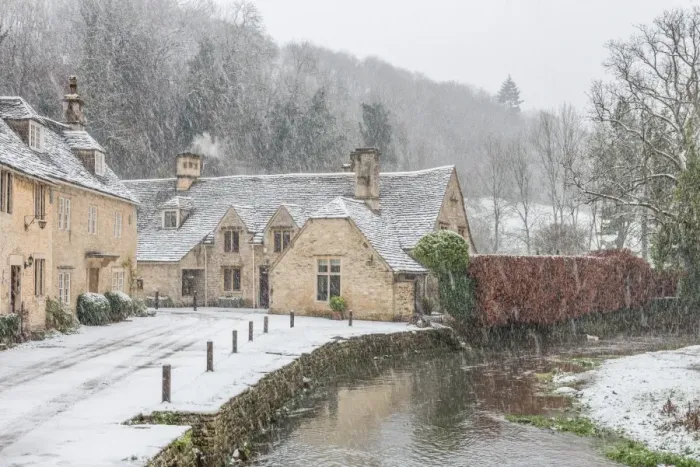 Framed Print : Snow covered houses by By Brook in Castle Combe with a dog enjoying a paddle, Wiltshire Framed Print : Snow covered houses by By Brook in Castle Combe with a dog enjoying a paddle, Wiltshire