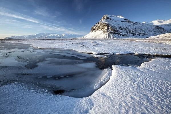 Snow covered landscape in winter with frozen pool, mountain and Vatnajokull Glacier